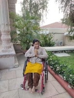 A smiling caregiver assisting a man with a wheelchair in a bright garden.