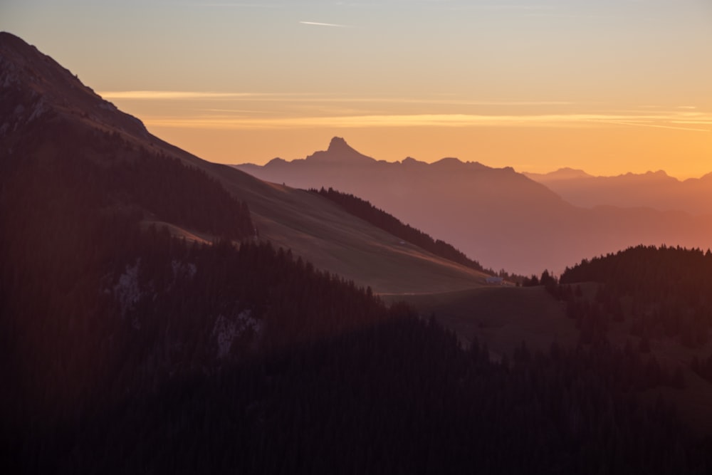 the sun is setting over the mountains in the distance