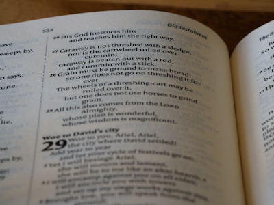 An open book displaying text from a religious scripture, specifically from the Old Testament. The verses discuss teachings and instructions from God, describing various practices including threshing. The text is in a clean, legible font with chapter and verse numbers clearly marked.