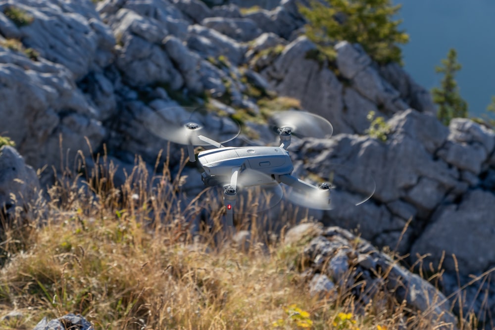 a white and black remote control flying over a mountain