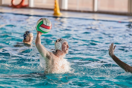 Close-up of an athlete's hands gripping the water polo ball mid-throw.
