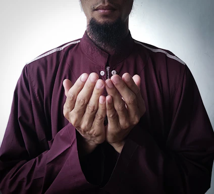 a man in a maroon shirt is holding his hands together