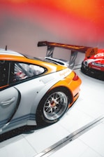 Warm, inviting automotive event setting with soft beige and deep gray tones accented by vibrant orange lighting.