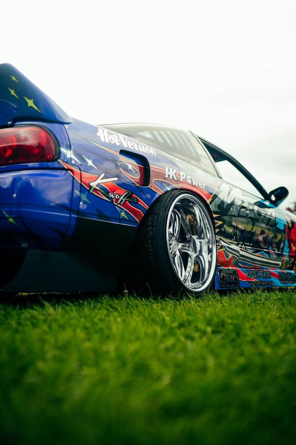 a blue sports car parked on top of a lush green field