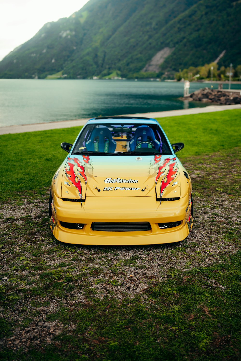a yellow sports car parked on the side of a lake