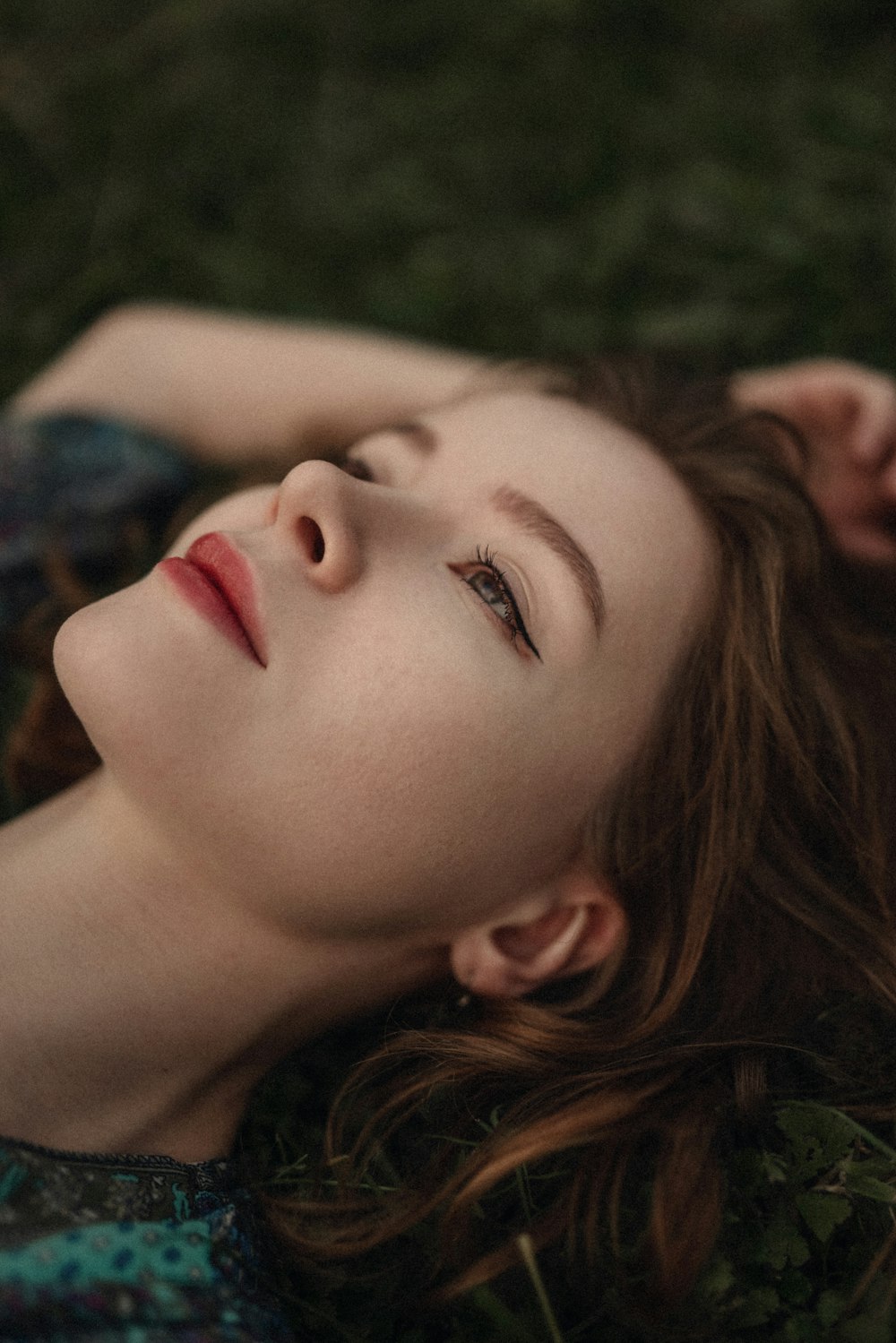 a woman laying on the grass with her eyes closed
