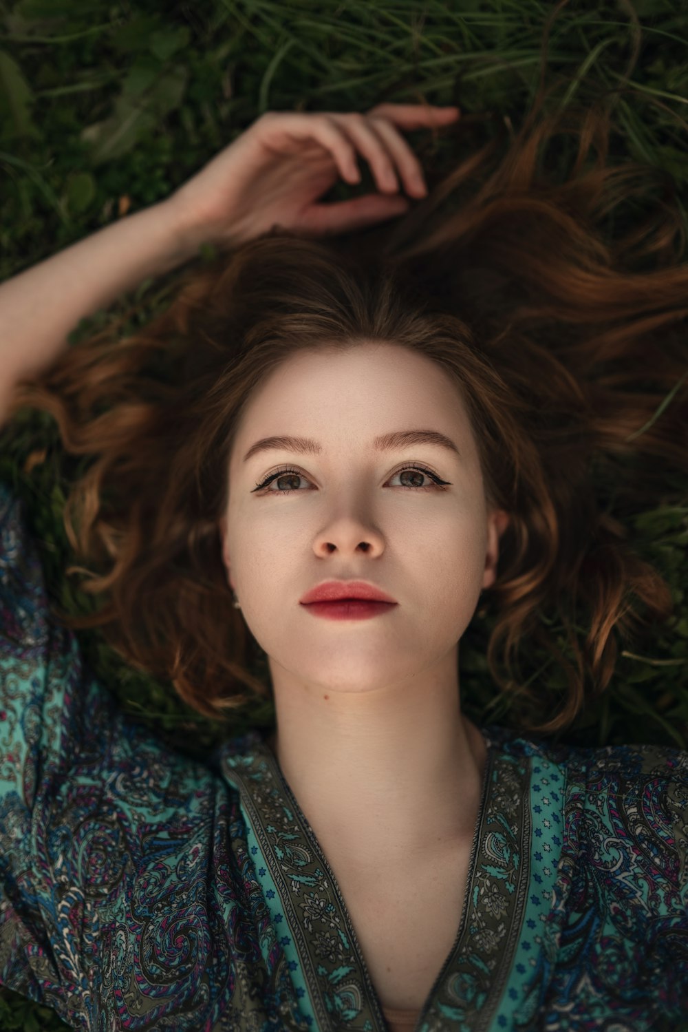 a woman laying in the grass with her hair blowing in the wind