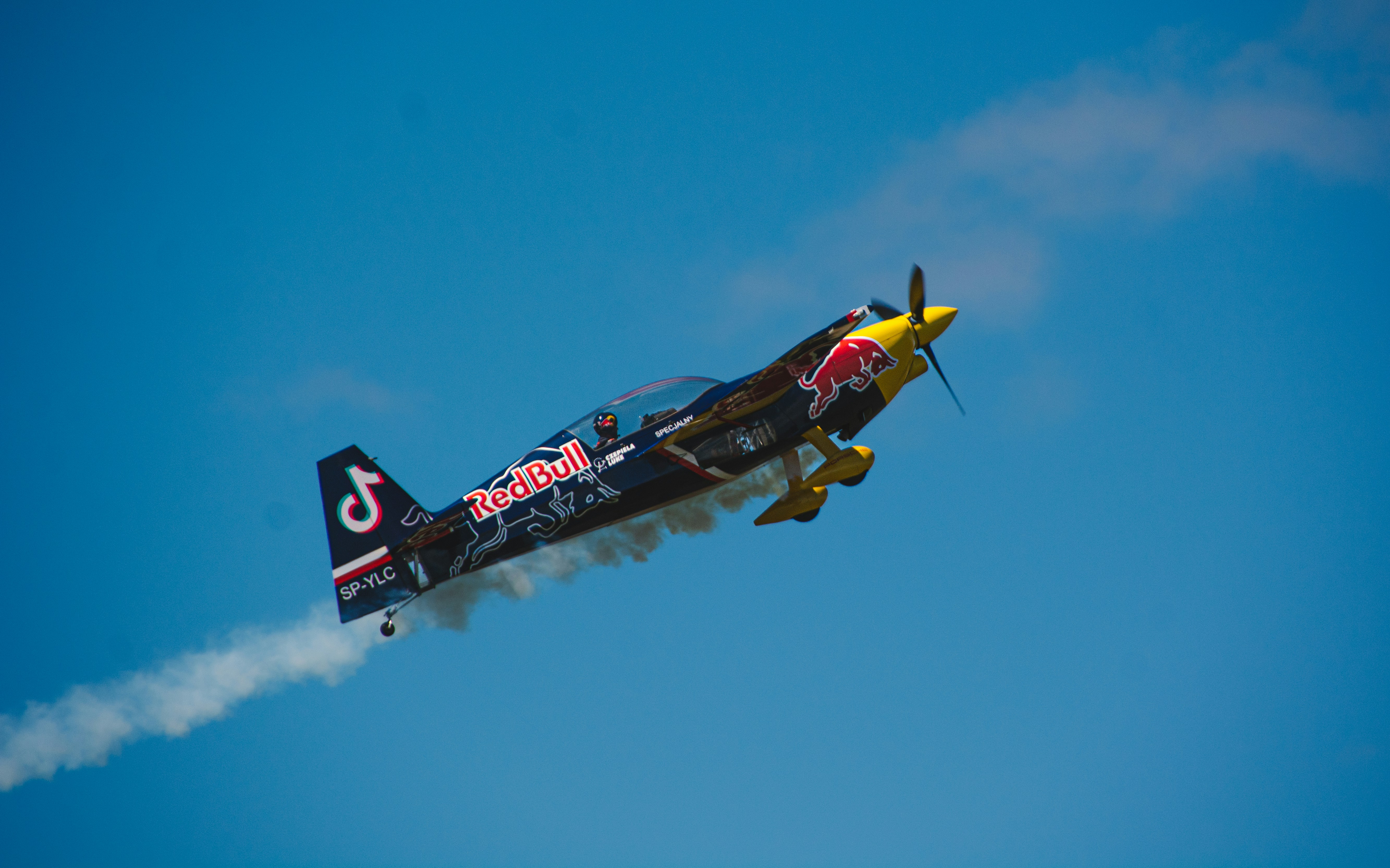 um avião vermelho e amarelo voando através de um céu azul