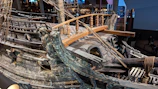 Close-up of craftsmen carefully restoring the wooden hull of the 1893 sailing cargo ship.