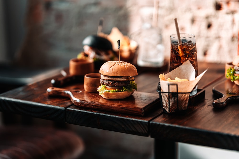 a wooden table topped with two hamburgers and drinks