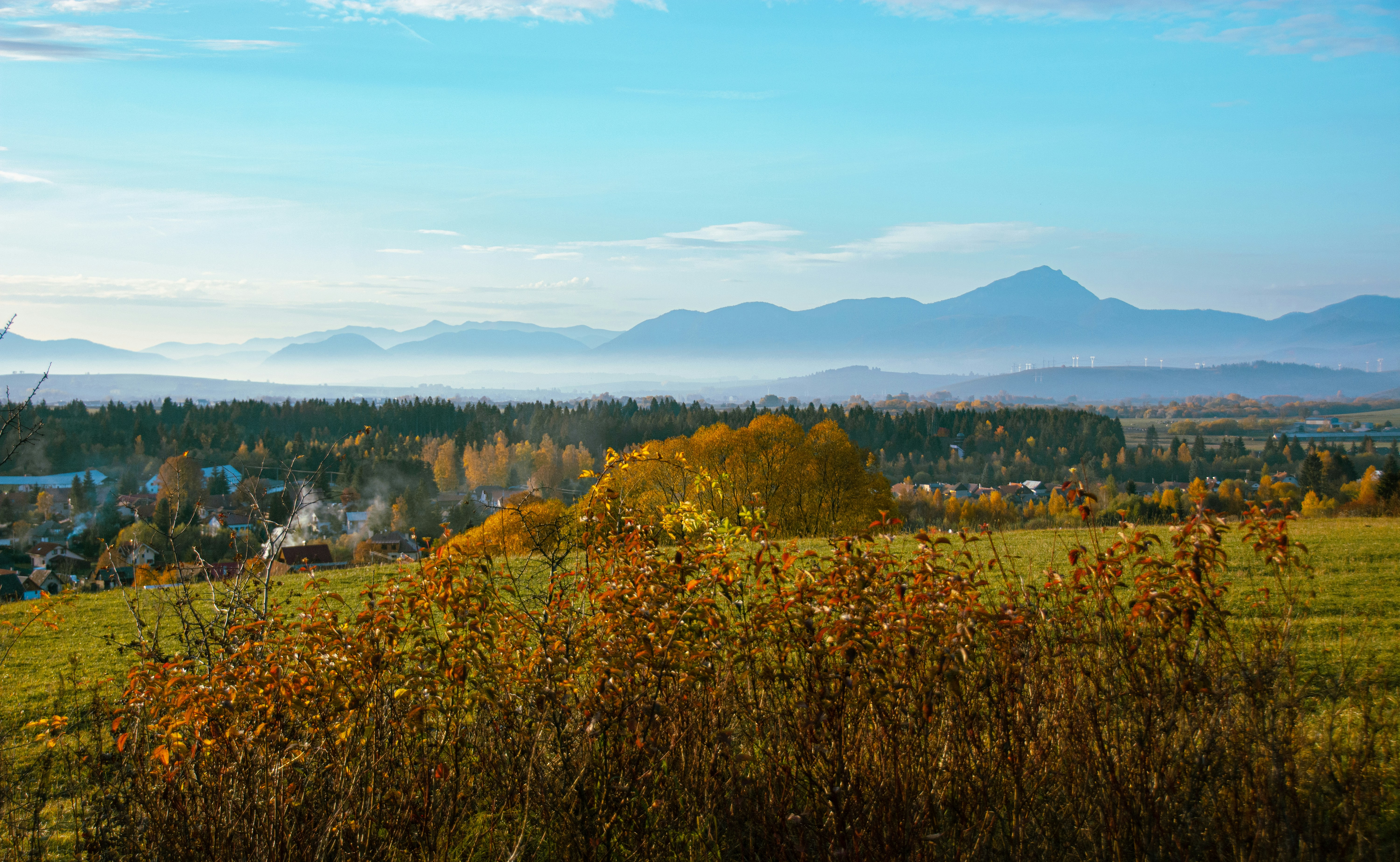 a scenic view of a town with mountains in the background