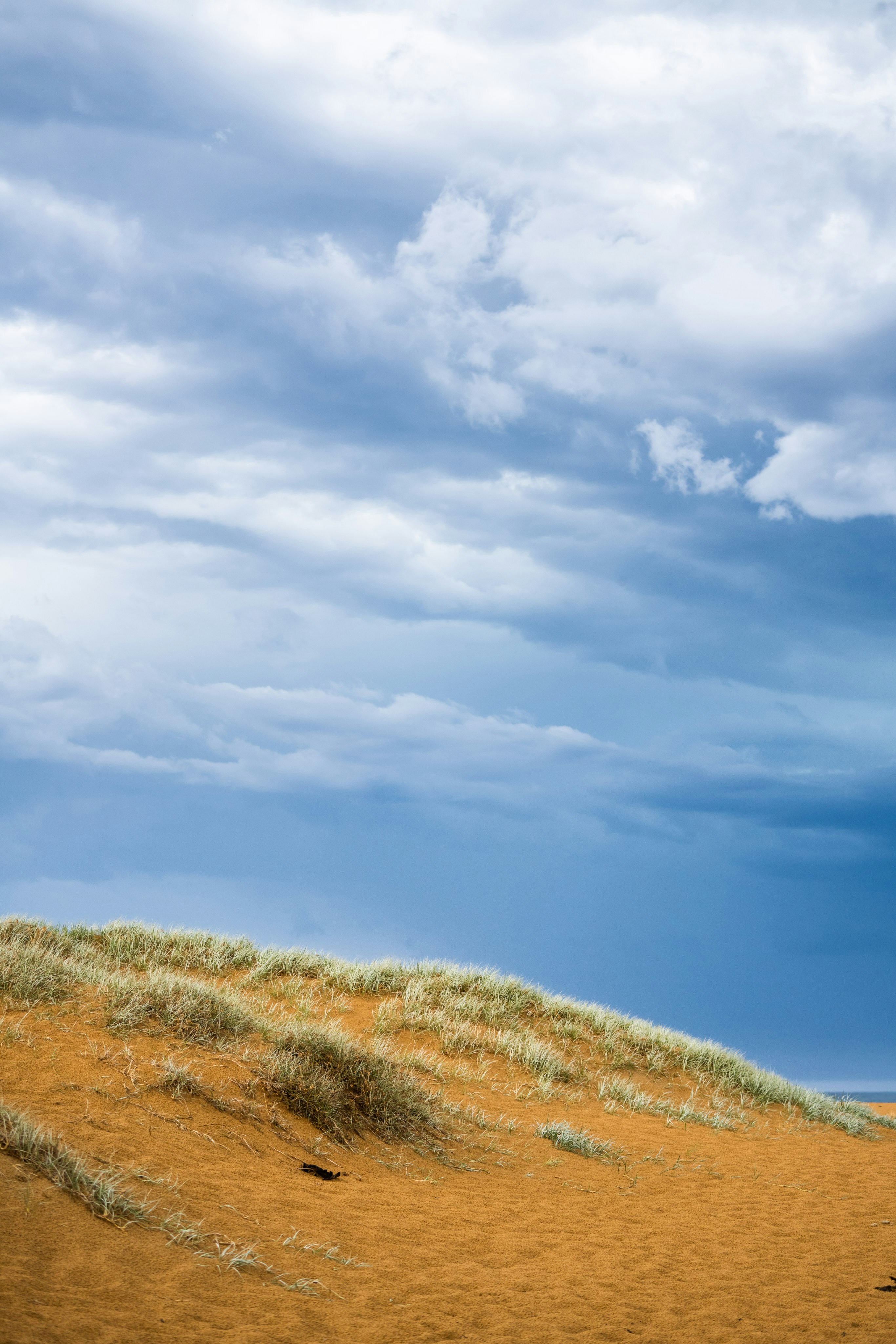 Un homme debout au sommet d’une colline de sable