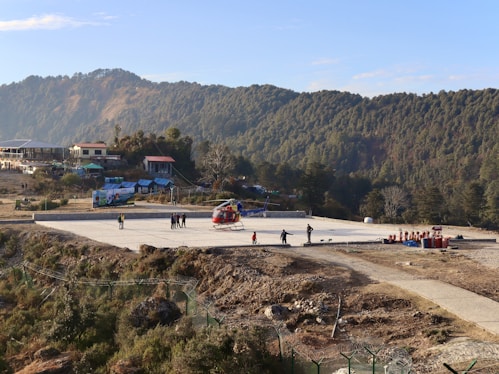 a group of people standing on top of a tarmac waiting to board helicopter for Char Dham