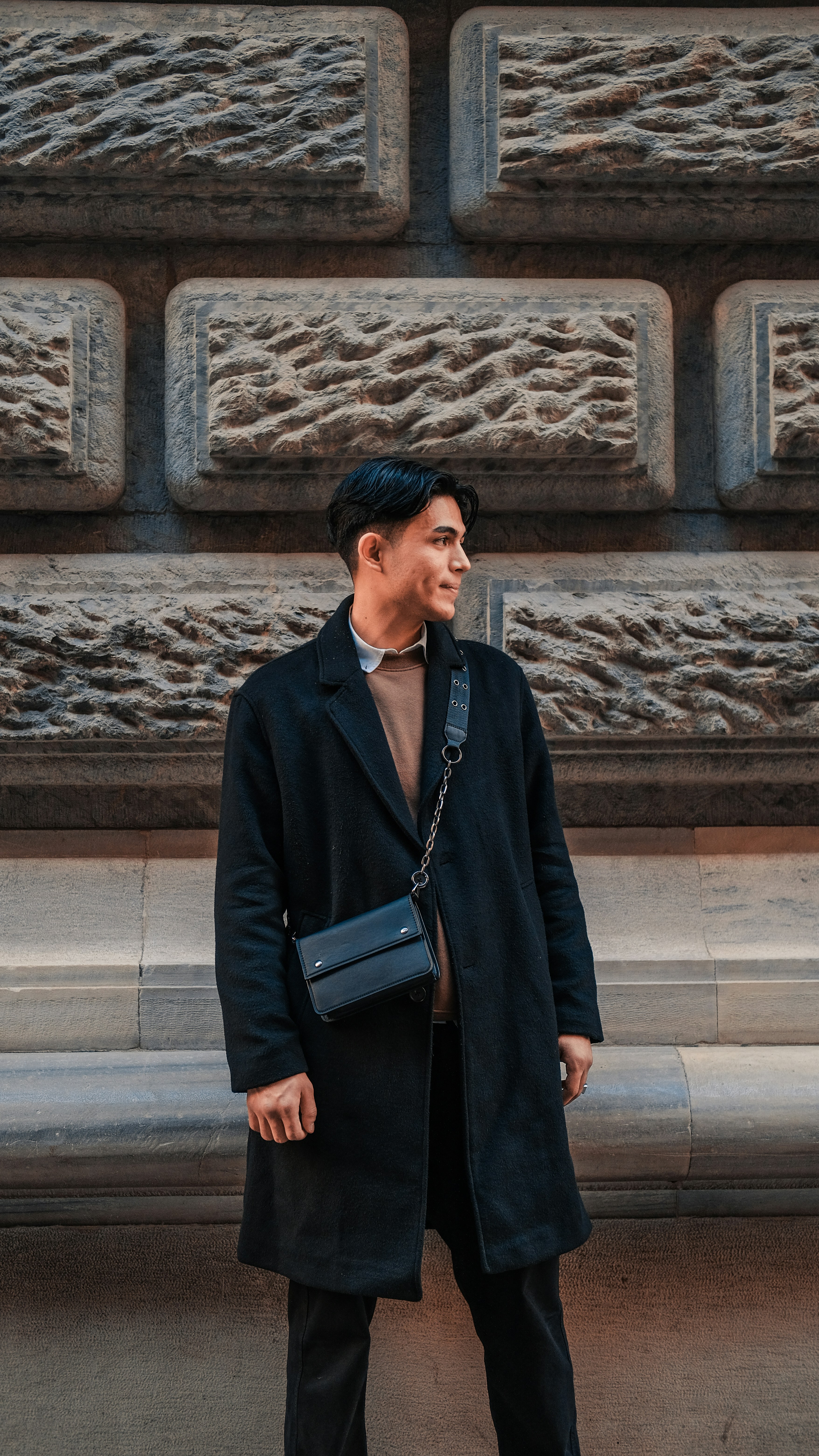 a man standing in front of a stone wall
