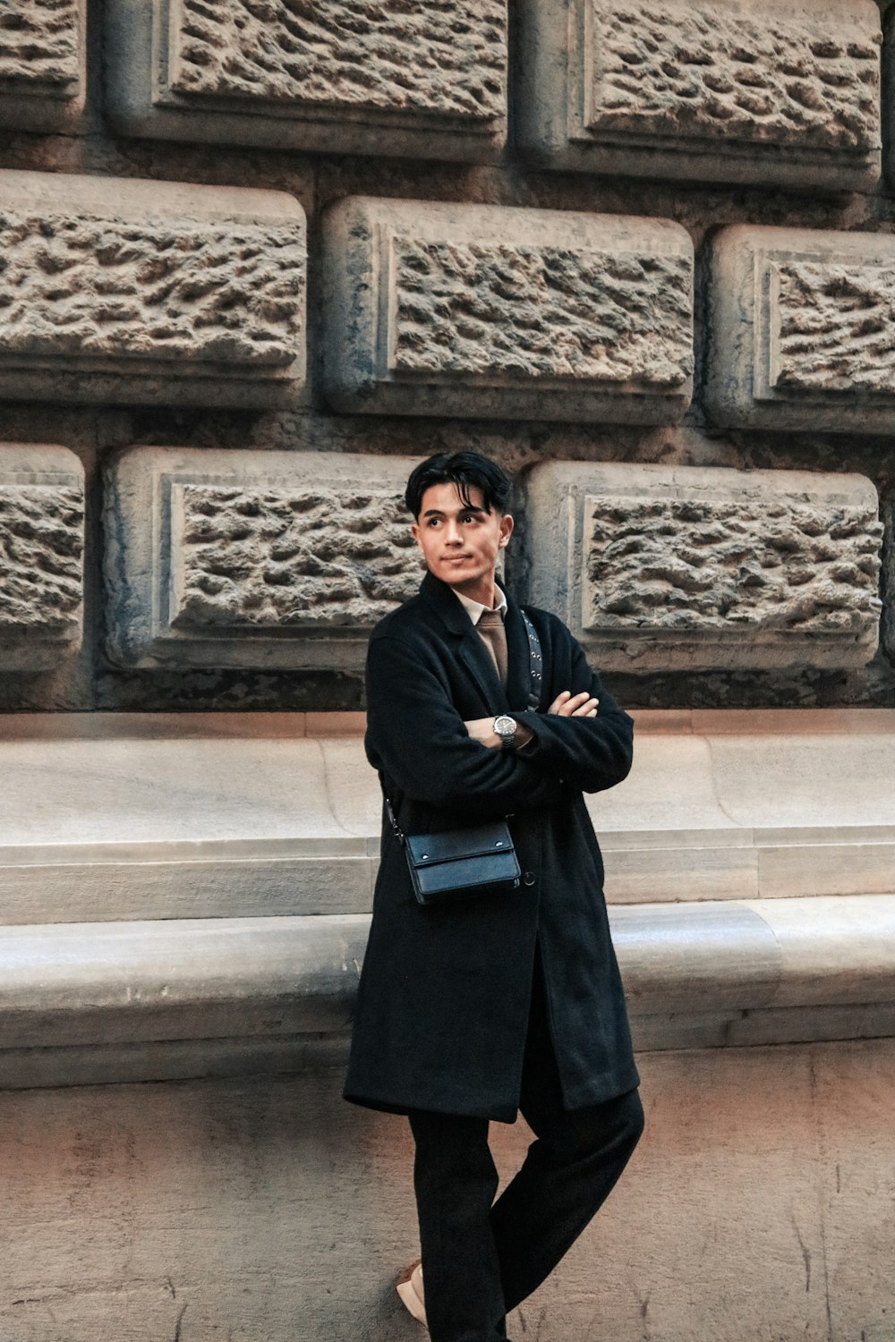 a man standing in front of a stone wall