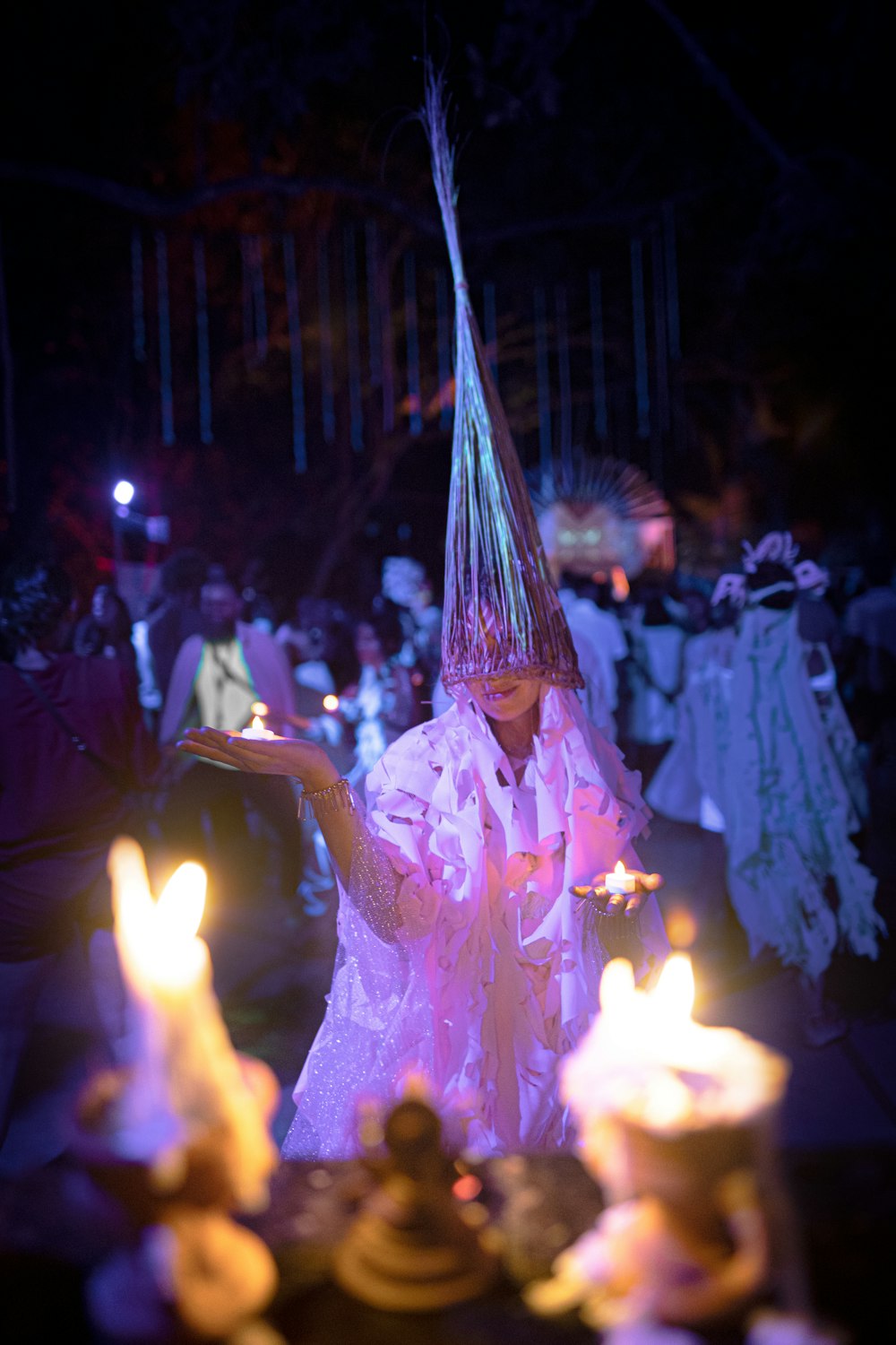 a woman in a white dress holding a tray of candles