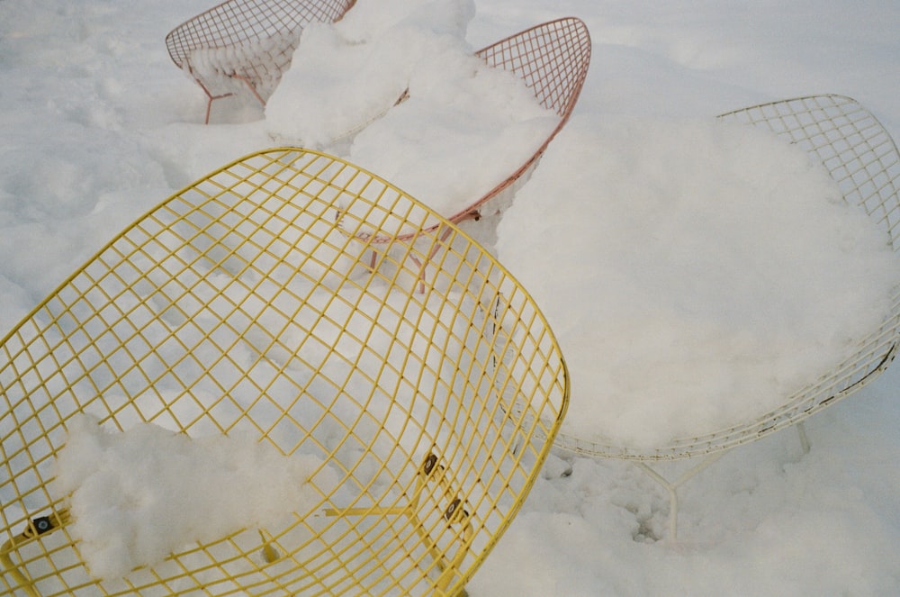 a yellow wire chair sitting in the snow