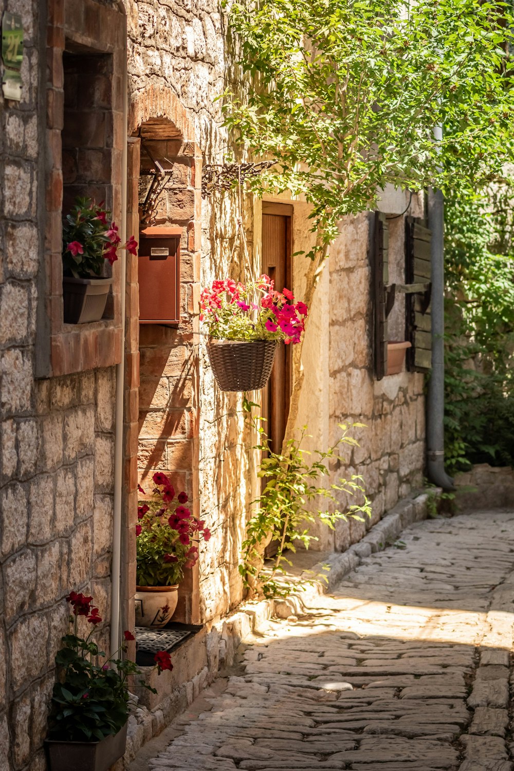 a cobblestone street with a stone building and flower boxes