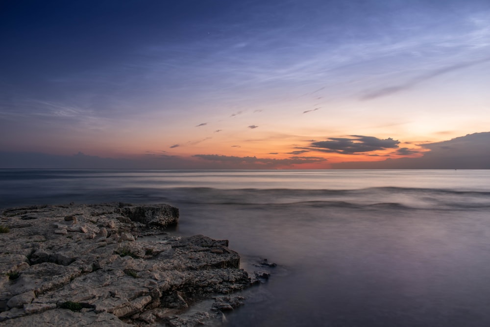 the sun is setting over the ocean on a cloudy day