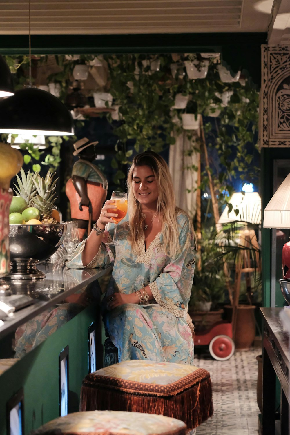 a woman standing in a kitchen holding a drink