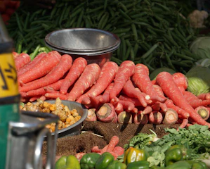Bright orange carrots with fresh green tops displayed on a market stall
