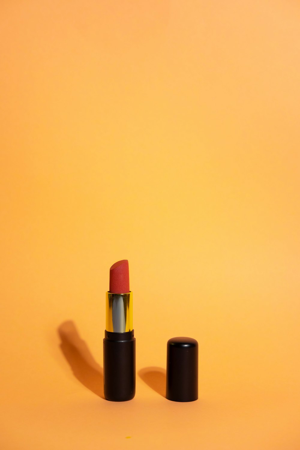 a red lipstick is sitting on a yellow background
