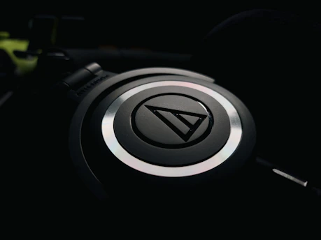 A sleek square icon with a headphone symbol glowing softly against a dark background.