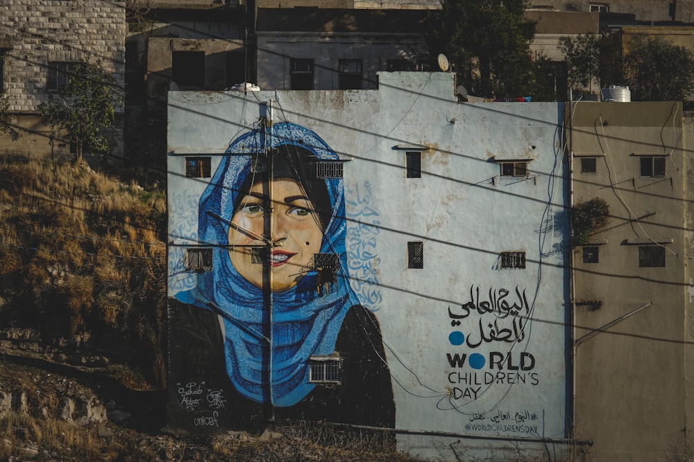 Un mural de una mujer con un pañuelo en la cabeza en el costado de un edificio