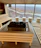 Sunlight filtering through lush plants inside the private sauna room, highlighting wooden benches.