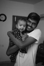 A smiling parent using baby sign language with a joyful infant in a cozy living room.