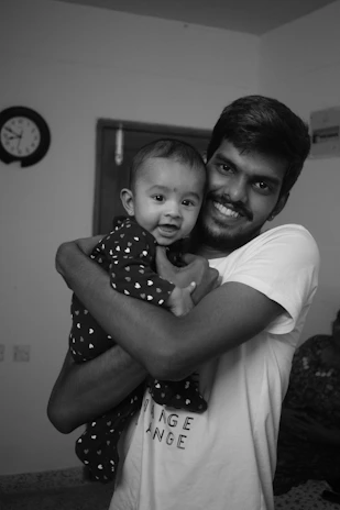 A smiling parent using baby sign language with a joyful infant in a cozy living room.