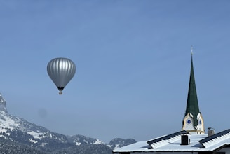 two hot air balloons flying over a church