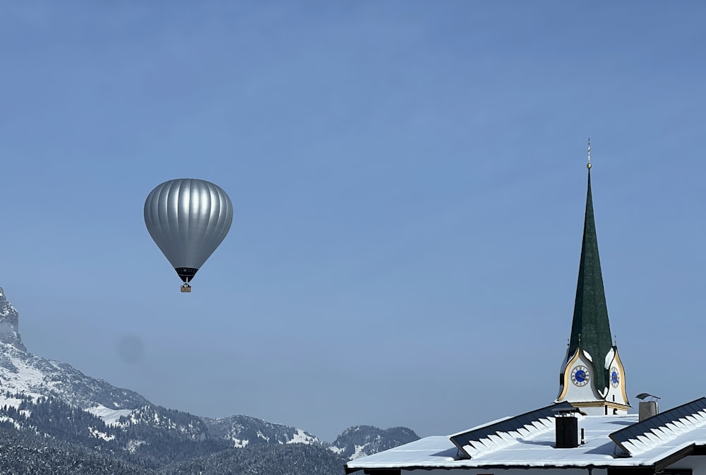 two hot air balloons flying over a church
