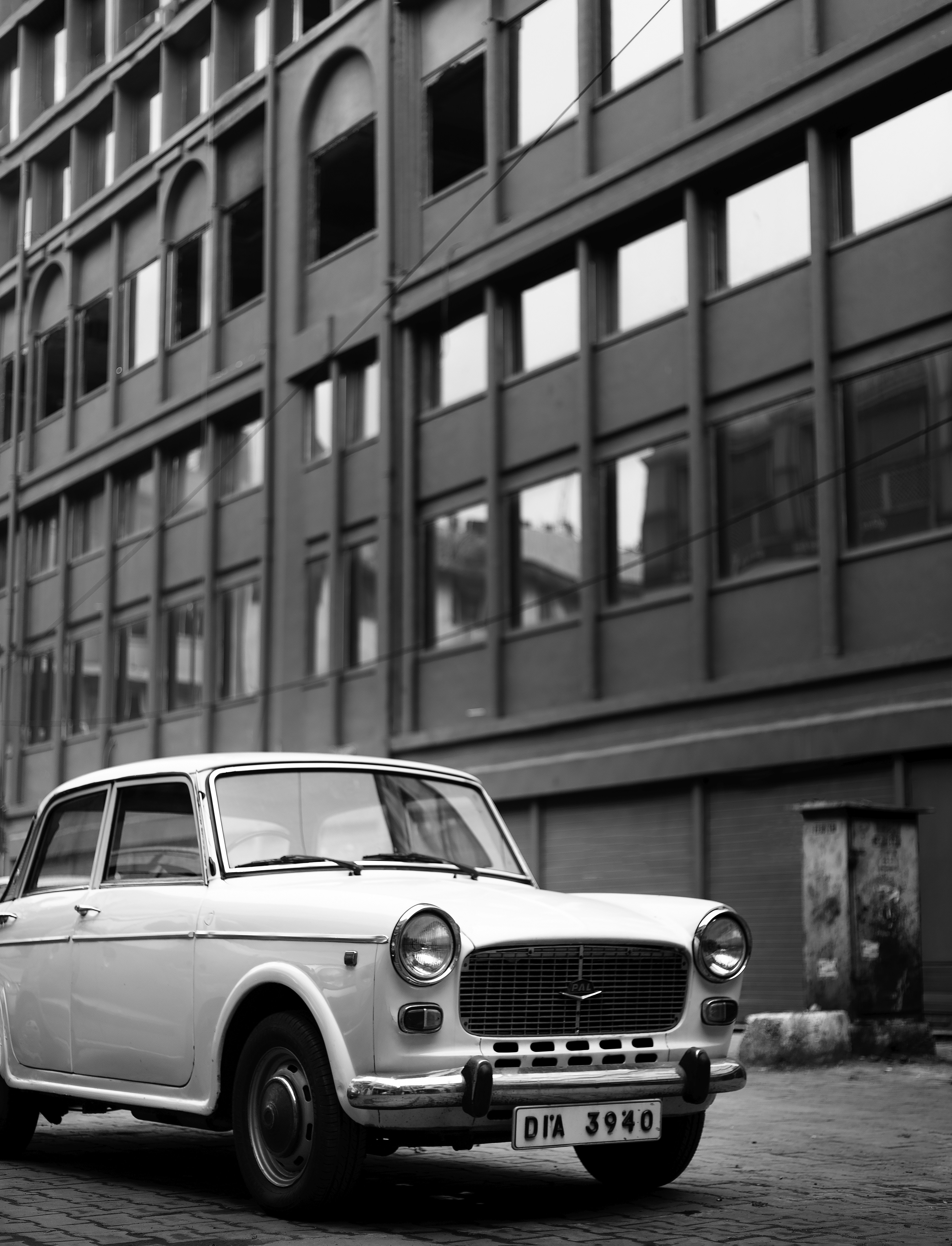 Ein weißes Auto parkt vor einem hohen Gebäude