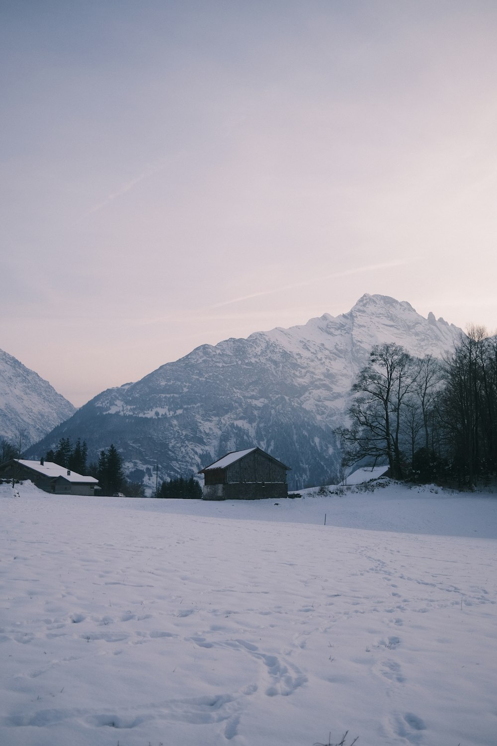 a snow covered field with mountains in the background