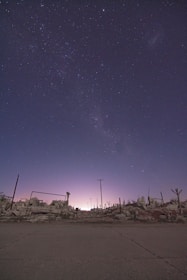 A nighttime version of a ruined village map, glowing lanterns casting eerie shadows across cobblestone streets.