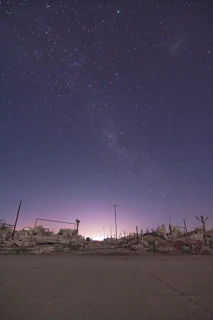 An atmospheric night scene with a violet gradient sky, ancient temples, and the hero standing watch.