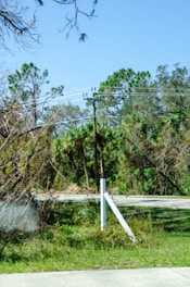 A postline technician carefully installing a sleek, modern real estate sign post on a sunny suburban lawn.