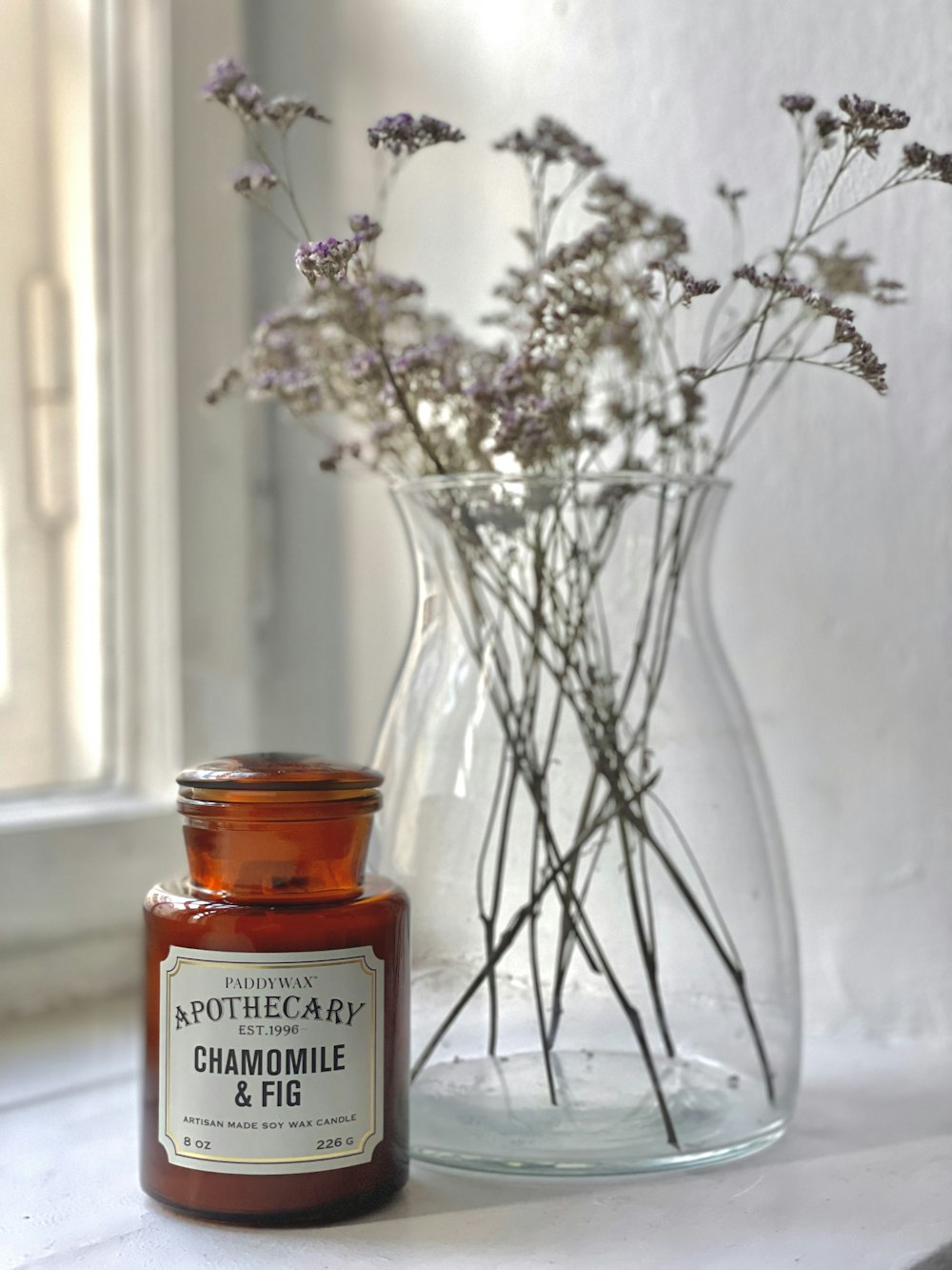 a bottle of chamomile next to a vase of flowers