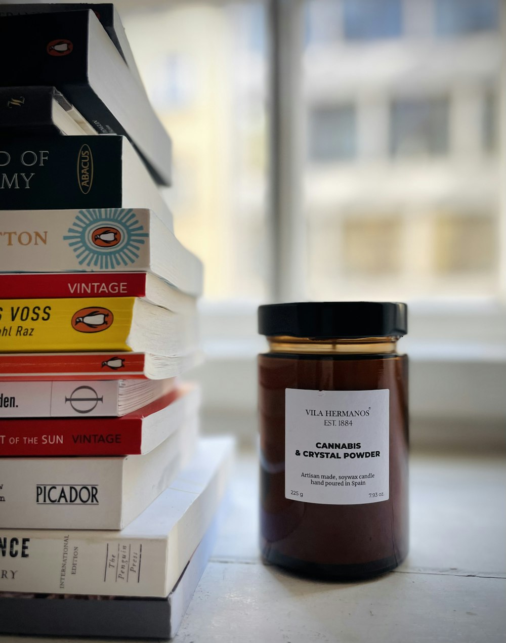 a stack of books sitting next to a jar of jam