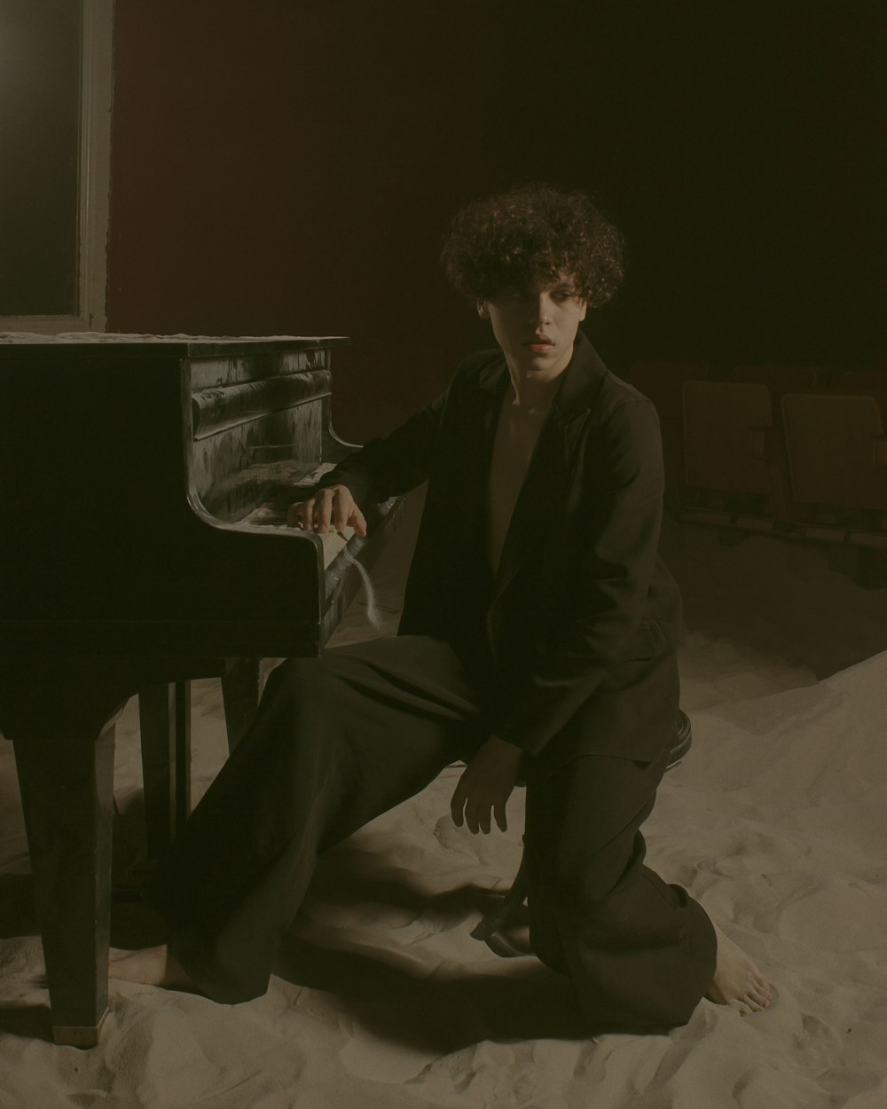 a man sitting on the ground next to a piano