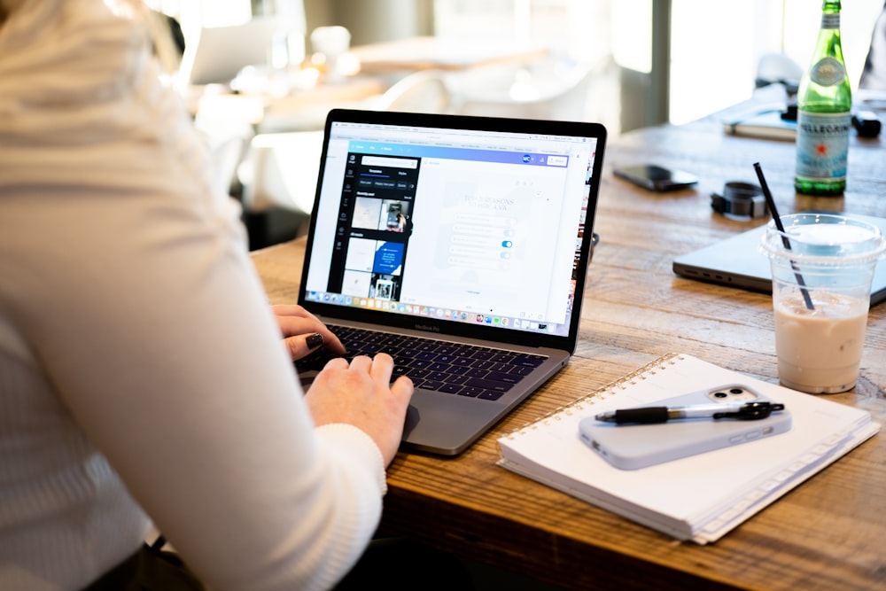 a woman sitting at a table using a laptop computer