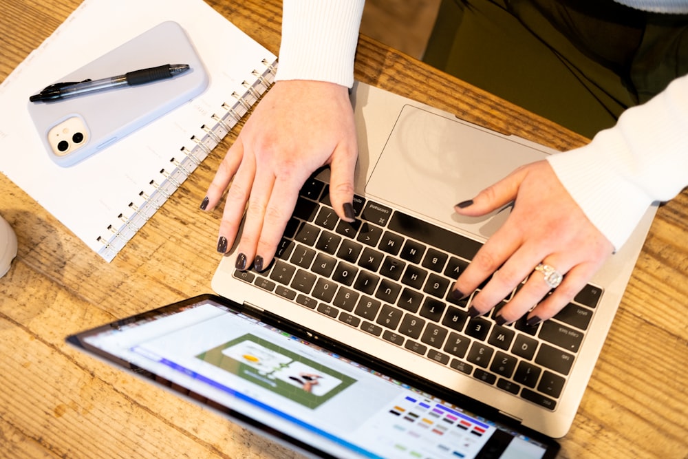 a person typing on a laptop on a wooden table