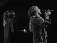 Close-up shot of waiz and péo sharing a microphone during a freestyle session.