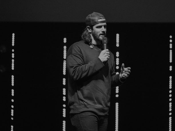 A person speaking into a microphone with a glowing digital interface in the background.