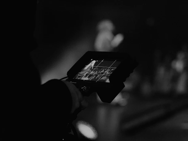 Cinematic shot of a videographer reviewing footage on a monitor, bathed in soft, moody light.
