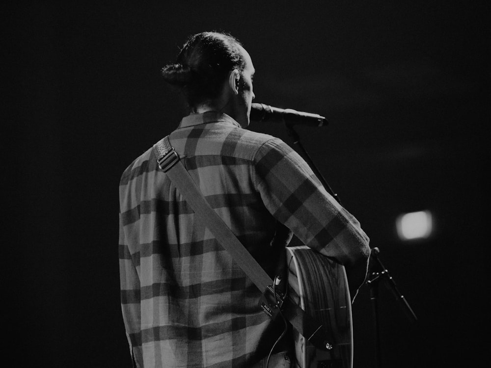 a man standing in front of a microphone holding a guitar