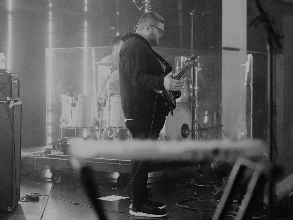 a man standing on a stage playing a guitar