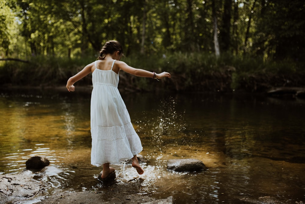 a woman in a white dress standing in a river