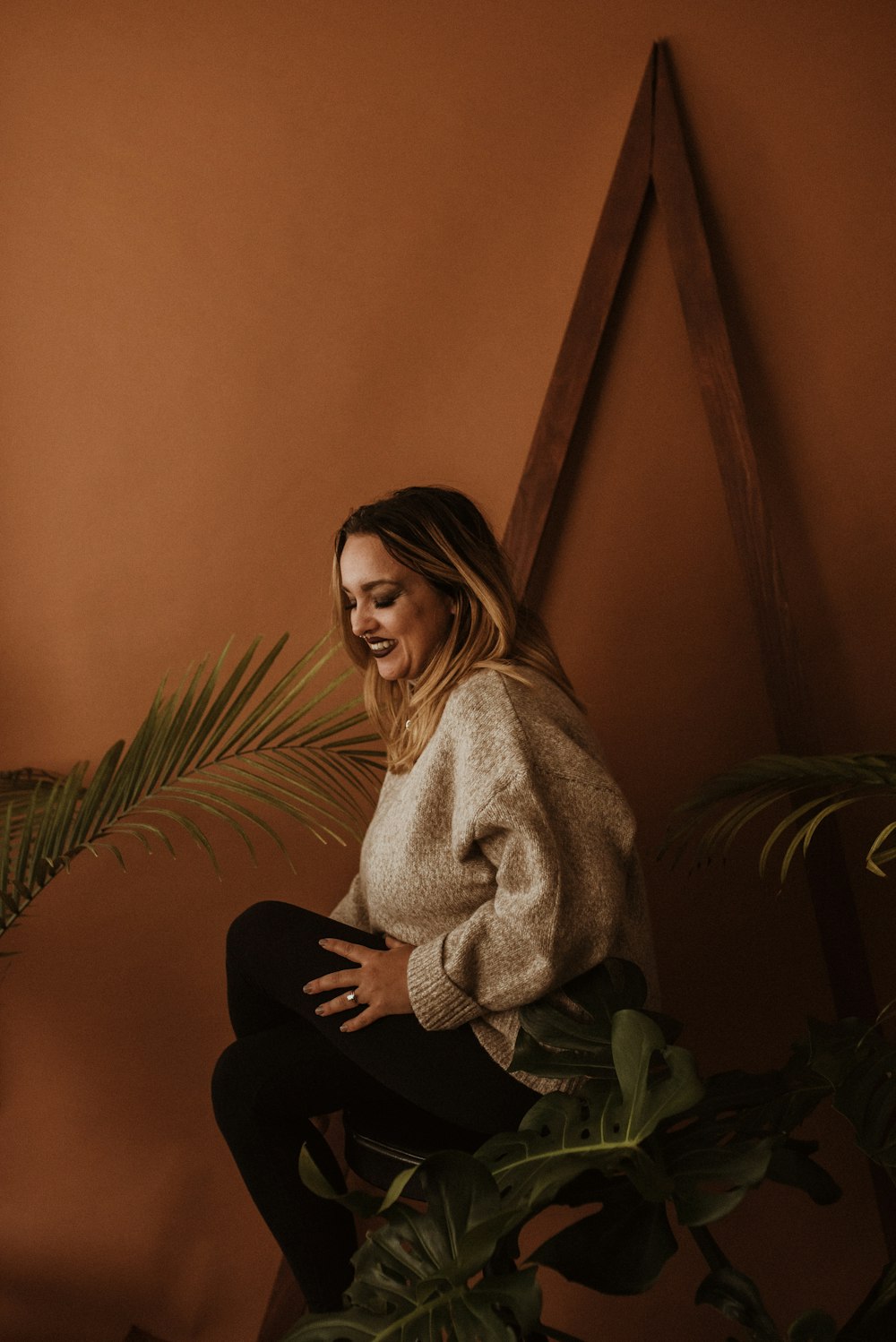 a woman sitting on a chair next to a plant